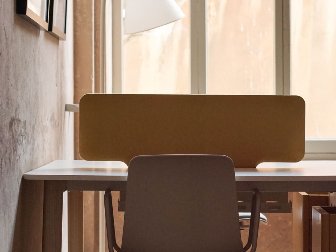Bureau équipé d’un fauteuil et d’une lampe devant une baie vitrée