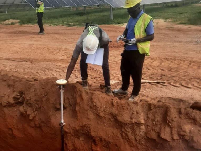 Relevé topographique au GPS devant les panneaux solaires de la centrale de Zano